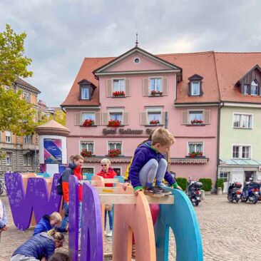 Dokumentation des Internationalen Tages der Demokratie in Konstanz mehrere Kinder spielen malen auf der Wortkonstruktion "Wort"